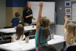 Girl raising hand in a class in the homeschool program
