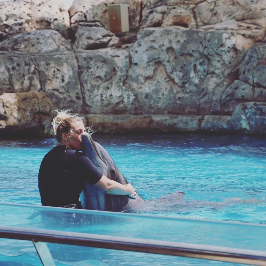 Dolphin trainer hugging and kissing a dolphin at the Texas State Aquarium.