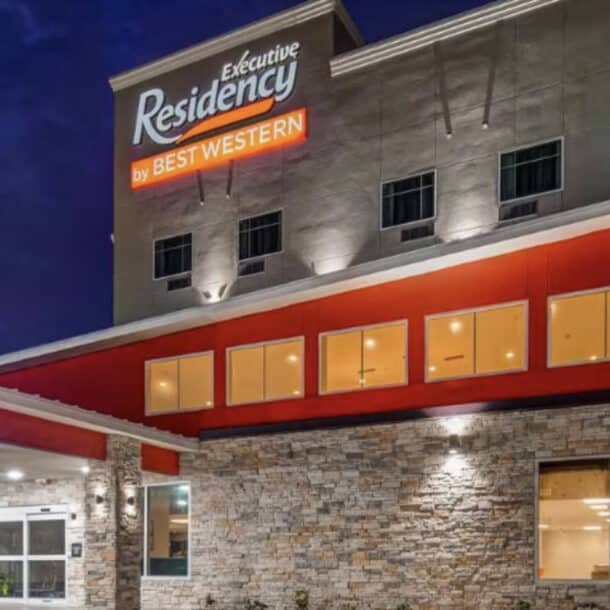 The exterior of an Executive Residency by Best Western hotel at night, with illuminated signs, large windows, and stone accents on the building.