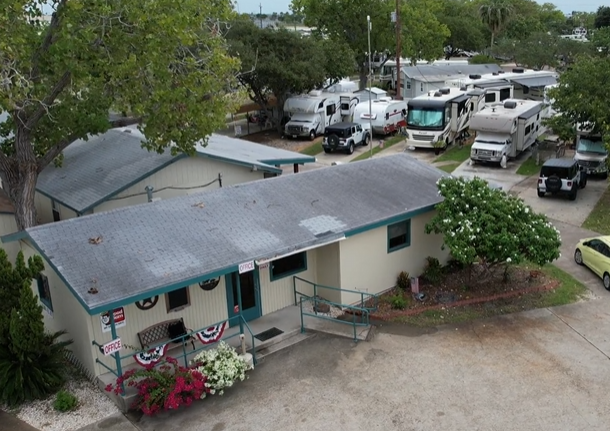 Aerial view of an RV park office building surrounded by shaded RV sites and parked motorhomes